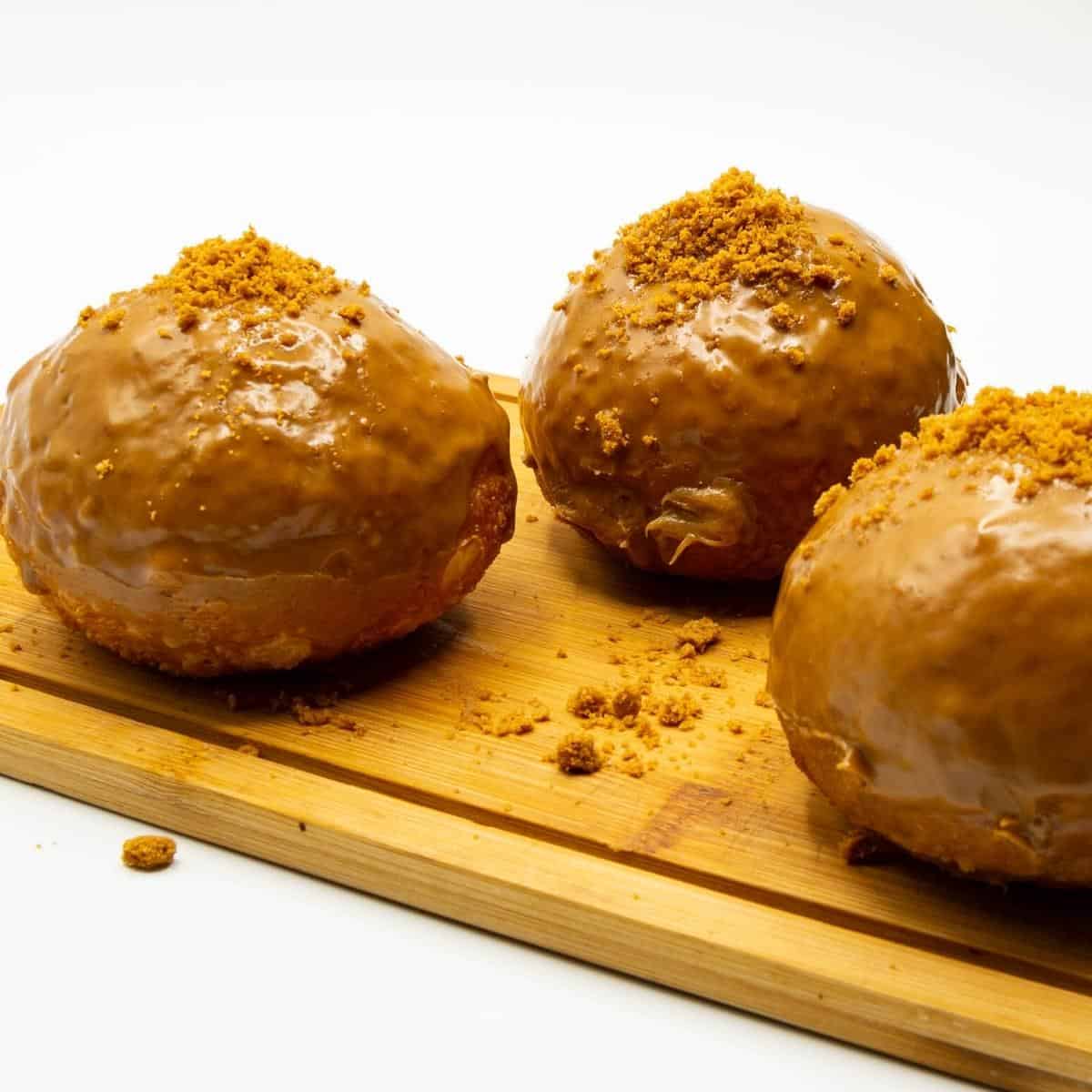 Three donuts on a wooden board.