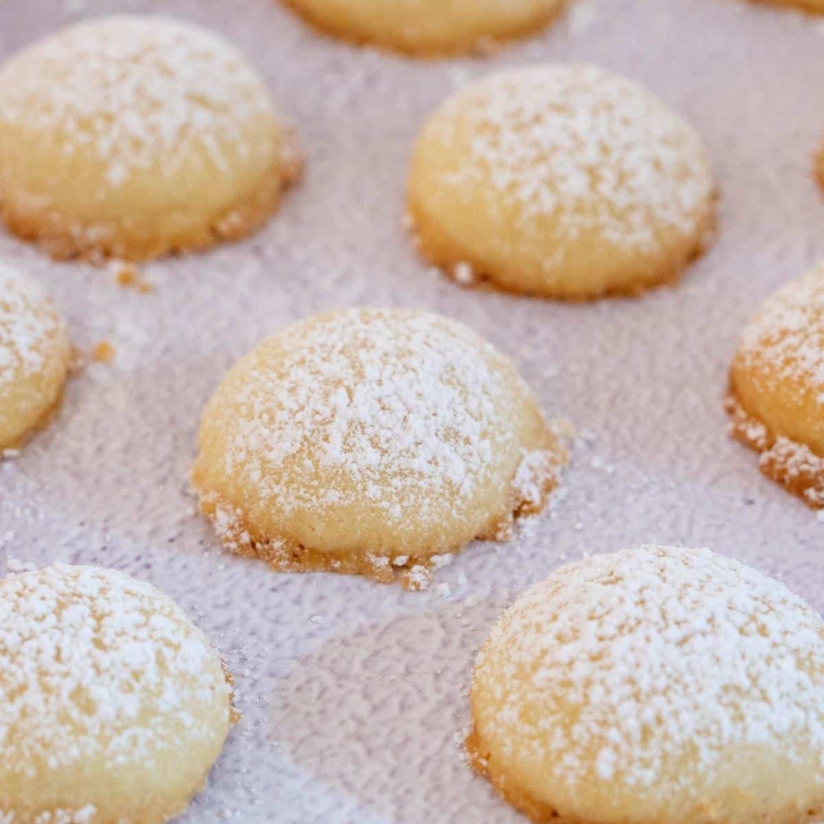 A white board with cookies dusted with powdered sugar. 