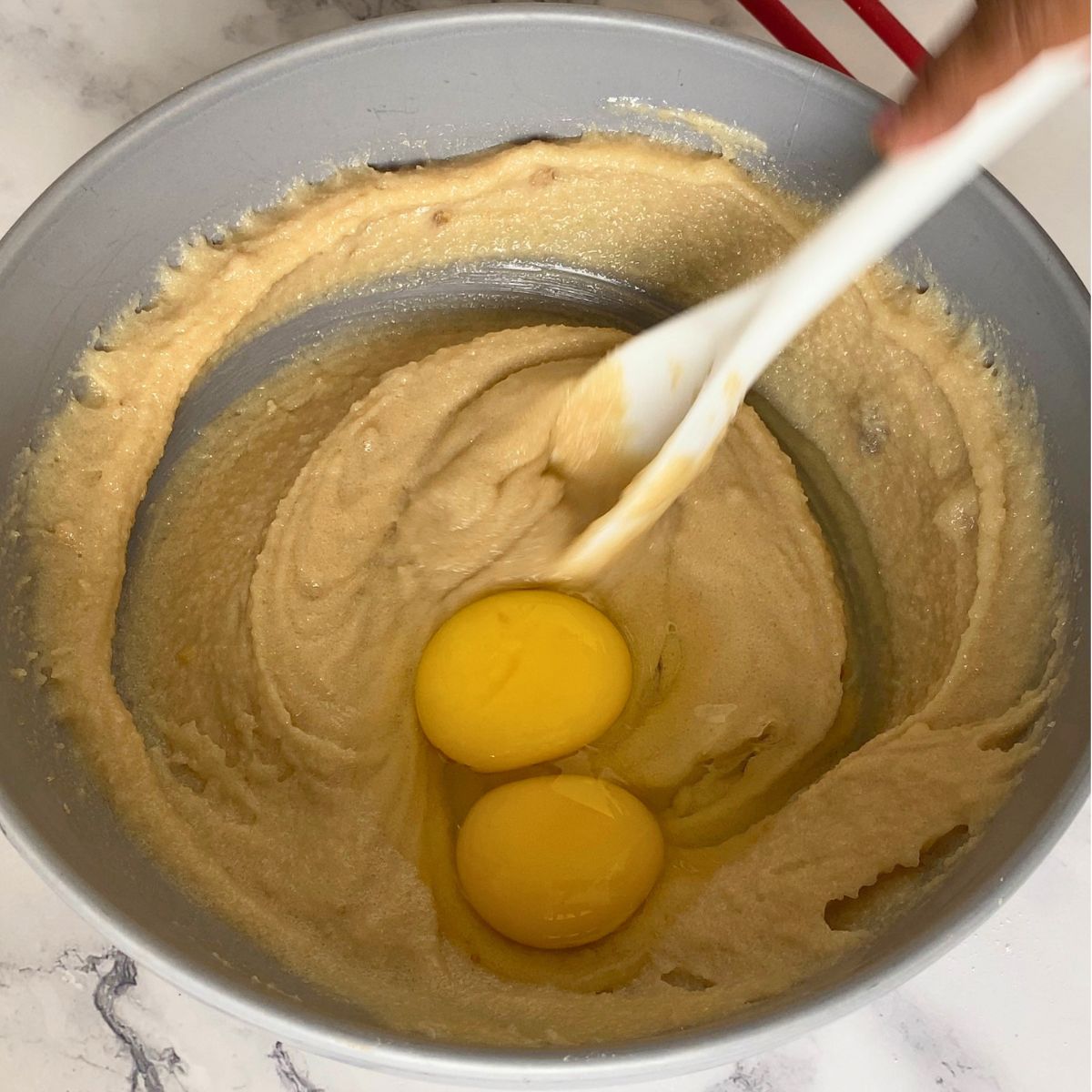Adding egg and egg yolk to the creamed butter sugar.