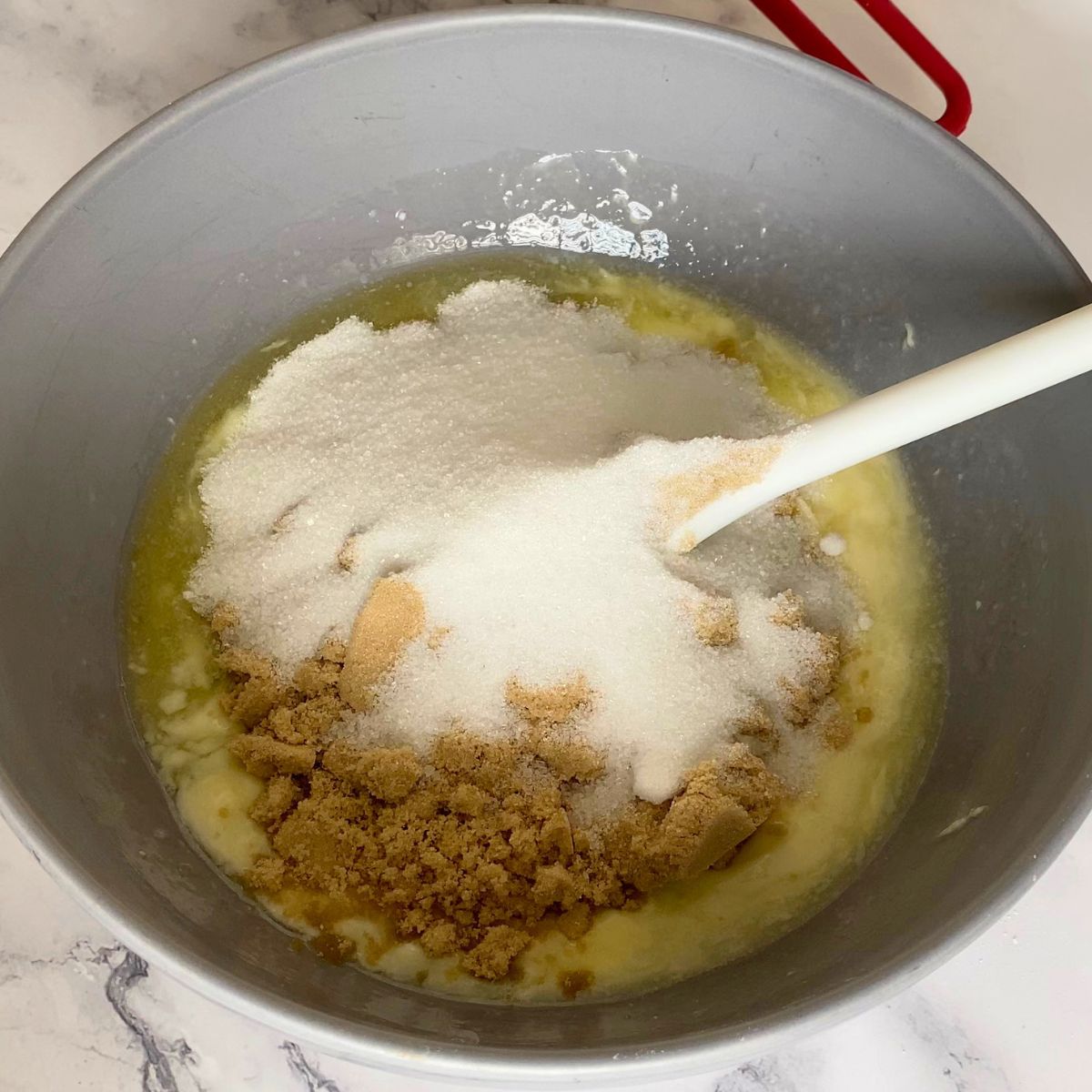 Creaming sugars with soft melted butter in a bowl.