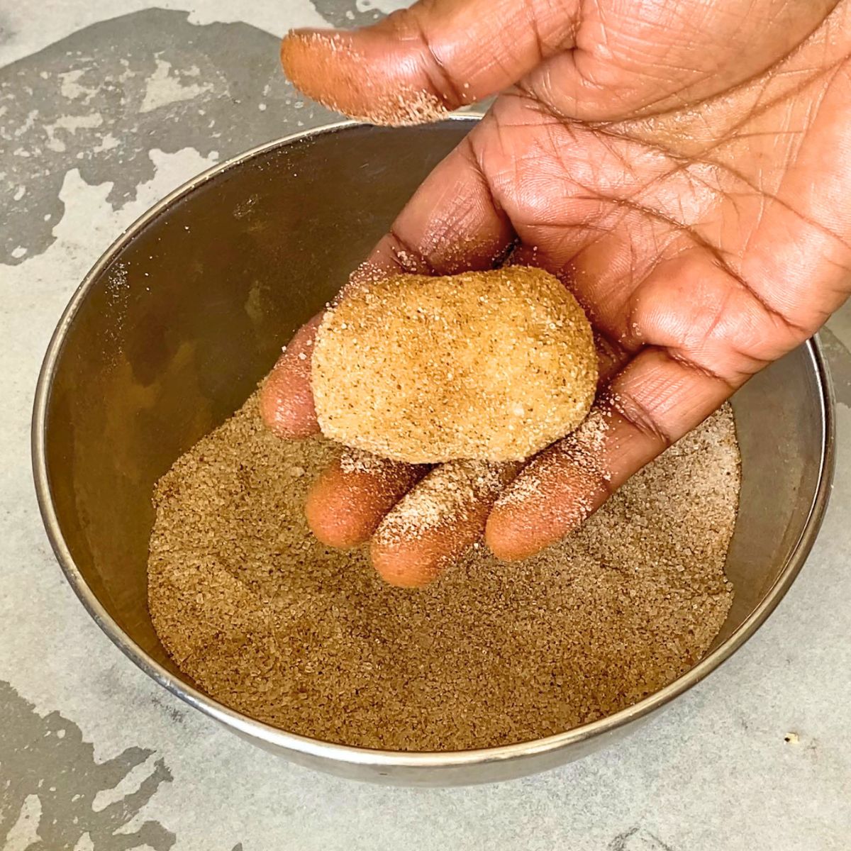 Coating the cookie dough in cinnamon sugar.