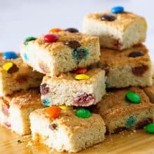 Cookie bars with M&Ms on a wooden board.