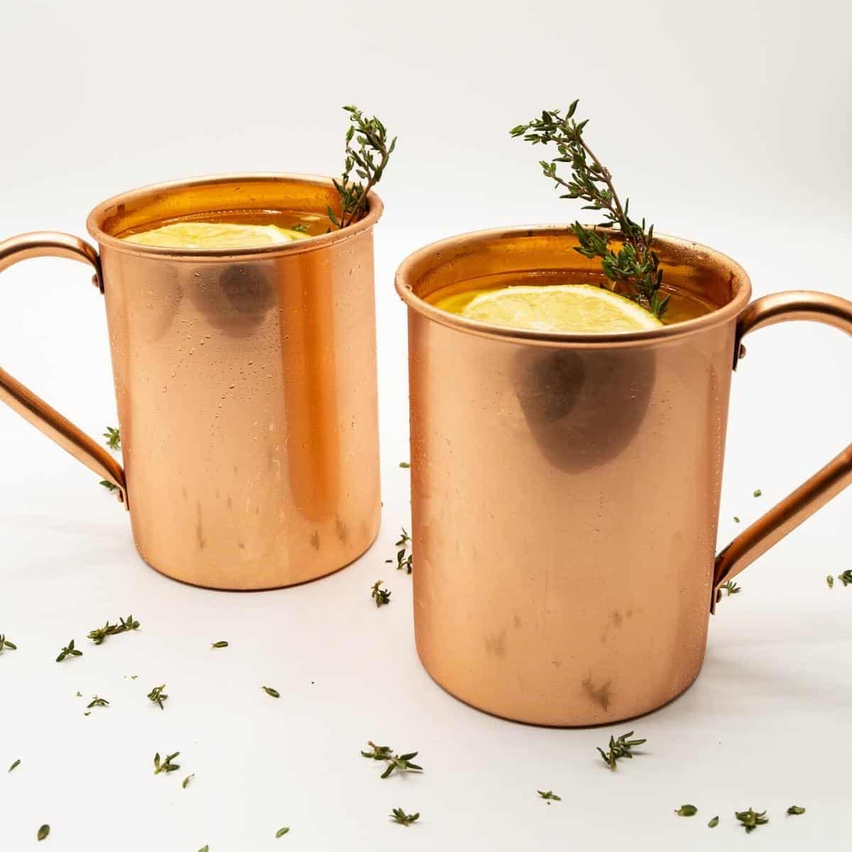 Two copper mugs with moscow mule over ice.