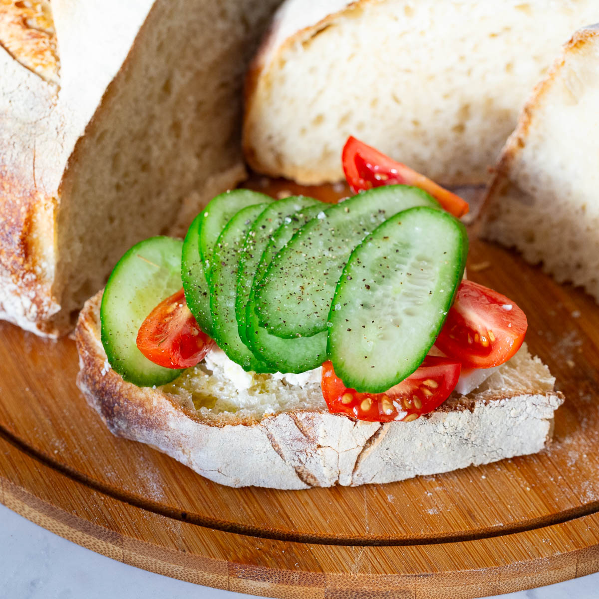 A sourdough slice with cheese, tomato and cucumber.