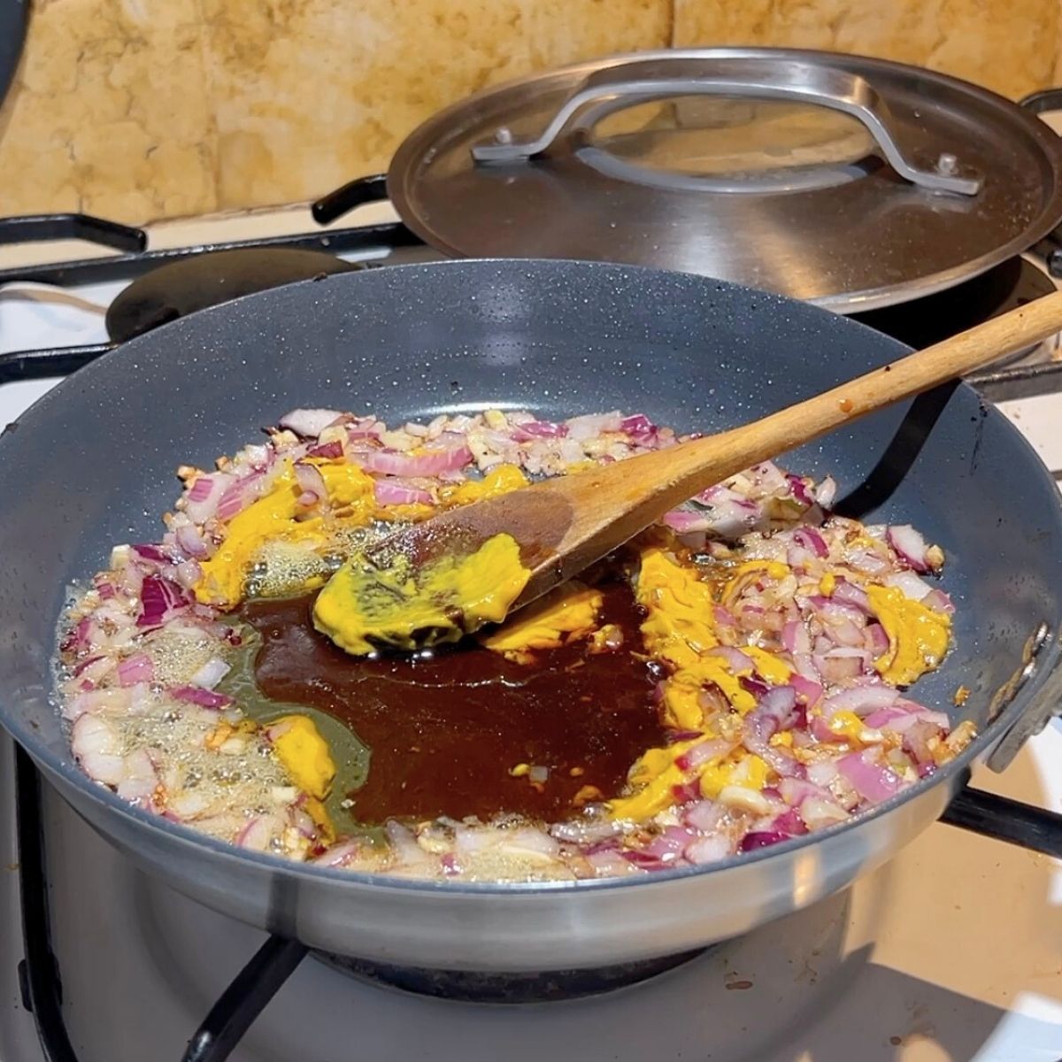 A skillet is preparing honey mustard chicken