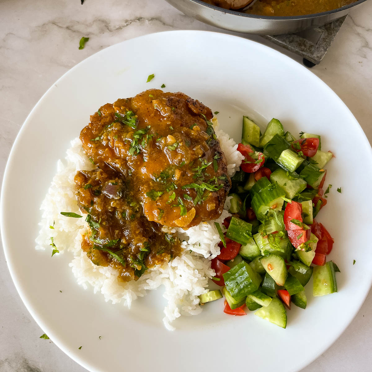 A white plate with rice and glazed chicken.