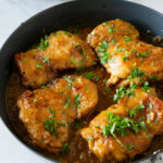 A skillet with chicken thighs.