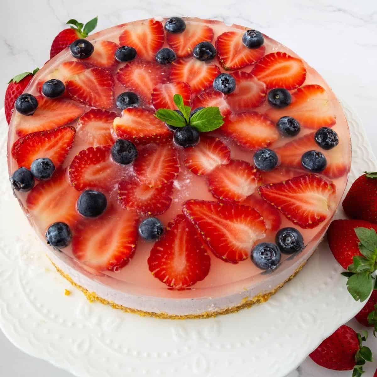 A mousse cake topped with jelly and fresh strawberries.