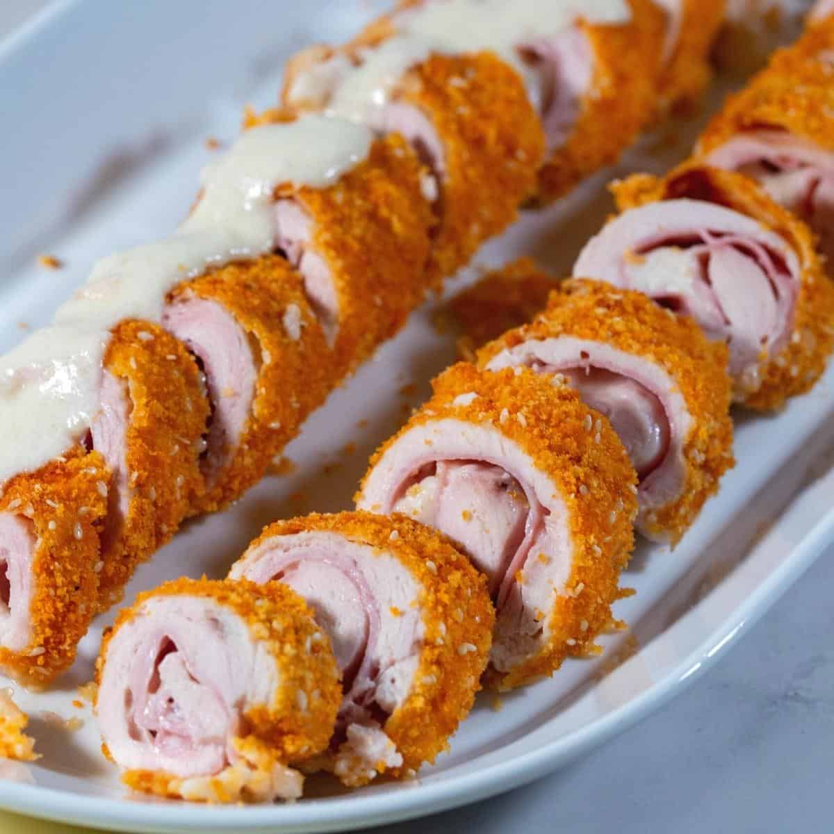 Sliced breaded chicken cordon blue with cheese sauce.