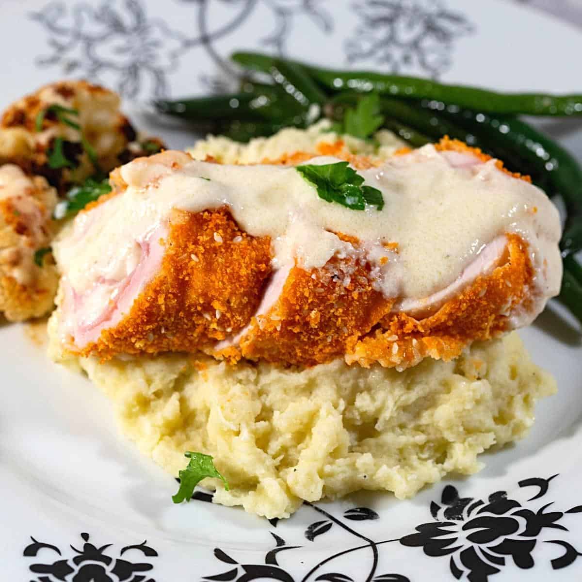 A plate with mashed potato and cordon bleu chicken.