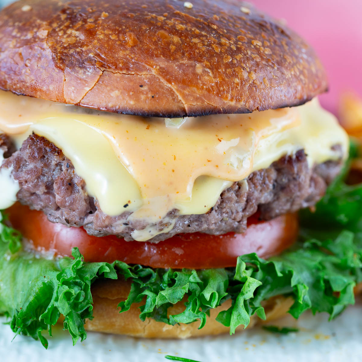 A plate with cheese burger on the table.
