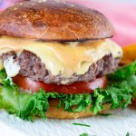 A cheesy hamburger on the table.