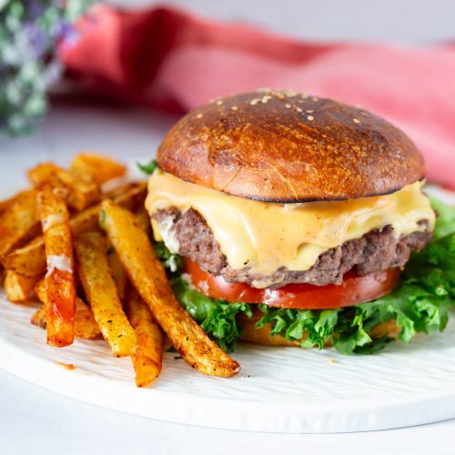 A classic burger with fies on the table.
