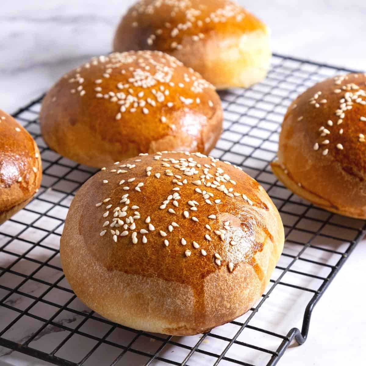 Baked burger buns on a cooling rack.