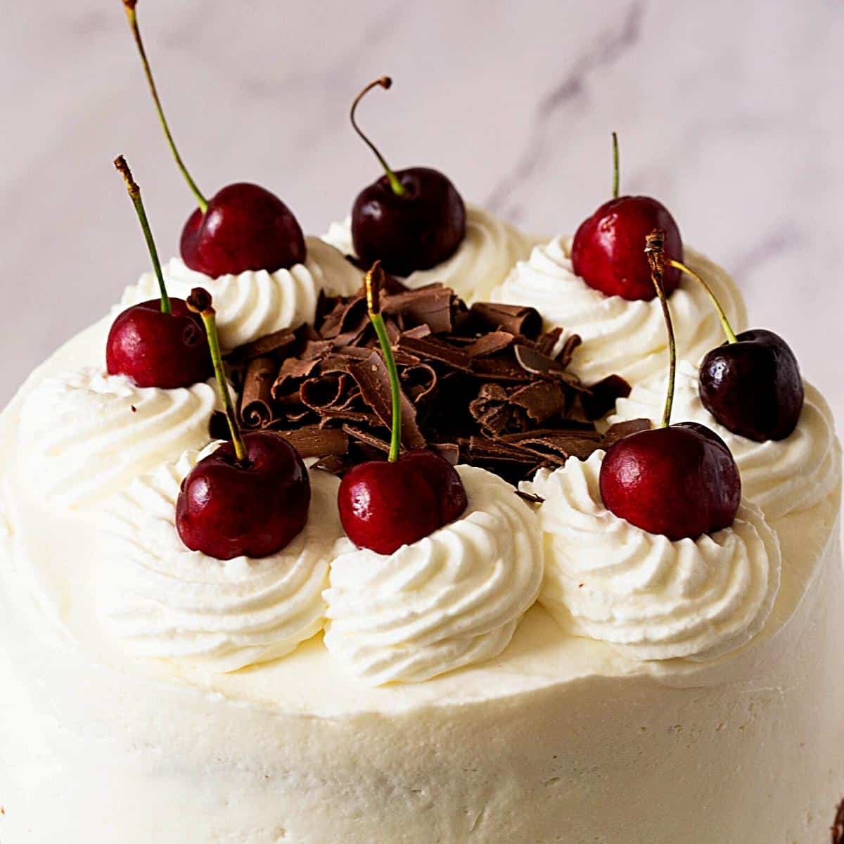 Piped whipped cream swirls on the black forest layer cake.