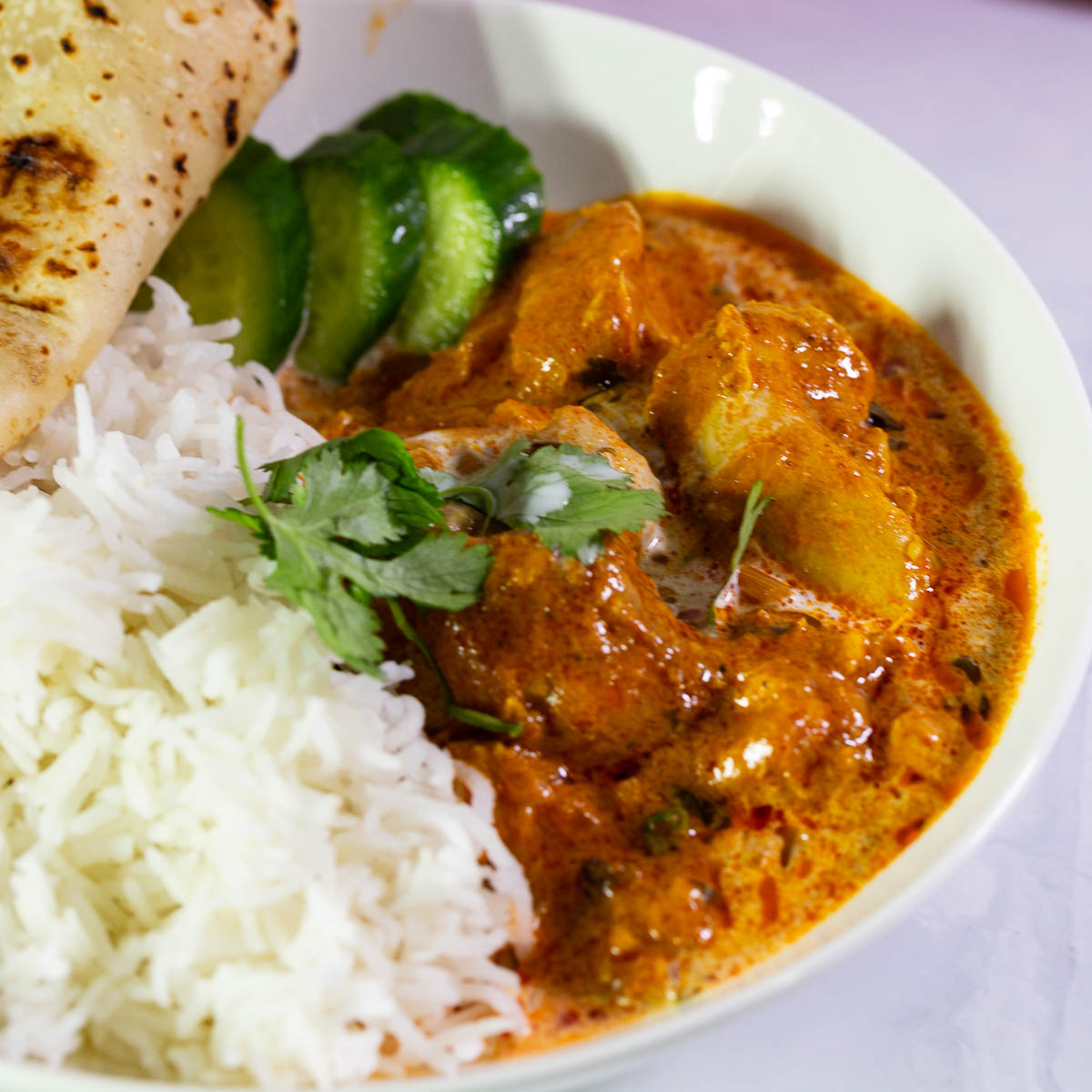 Chicken tikka masala in a white plate over rice.