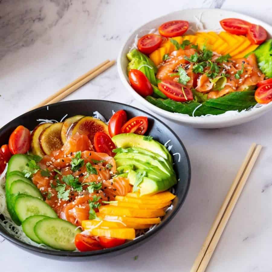 A bowl with fresh salmon, dressing and fresh salad.