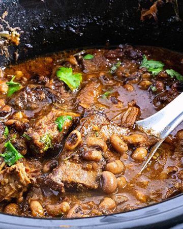 A slow cooker with black eyed peas and shot ribs.
