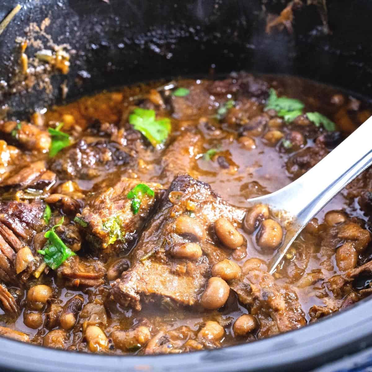 A slow cooker with black eyed peas with short ribs.