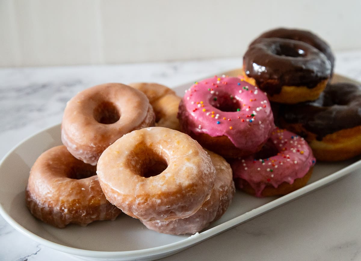 A platter with sugar glazed and chocolate glazed donuts.