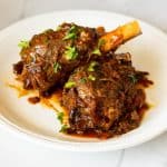 A plate with lamb shanks and gravy.