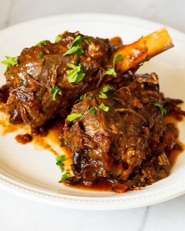 A plate with lamb shanks and gravy.