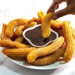 A plate with churros and chocolate sauce.