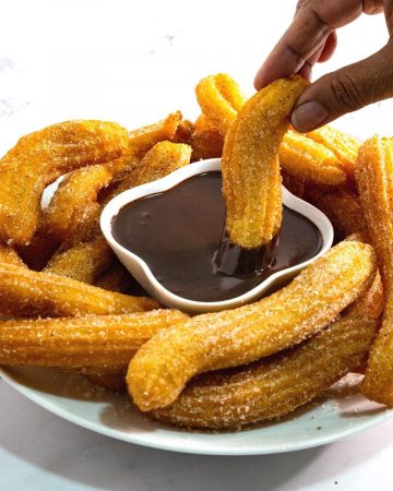 A plate with churros and chocolate sauce.