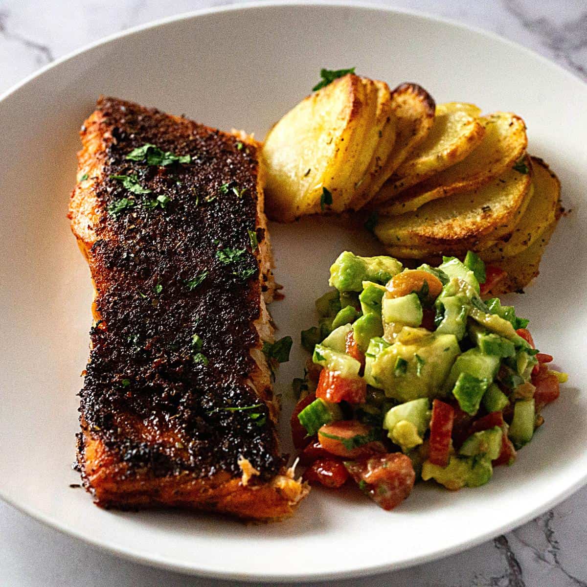 A plate with salmon salad and potatoes.