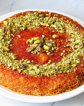 A baked knafeh on a large white plate.