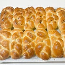 Challah braided dinner rolls on a cooling rack.