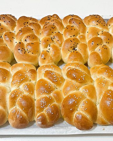Challah braided dinner rolls on a cooling rack.