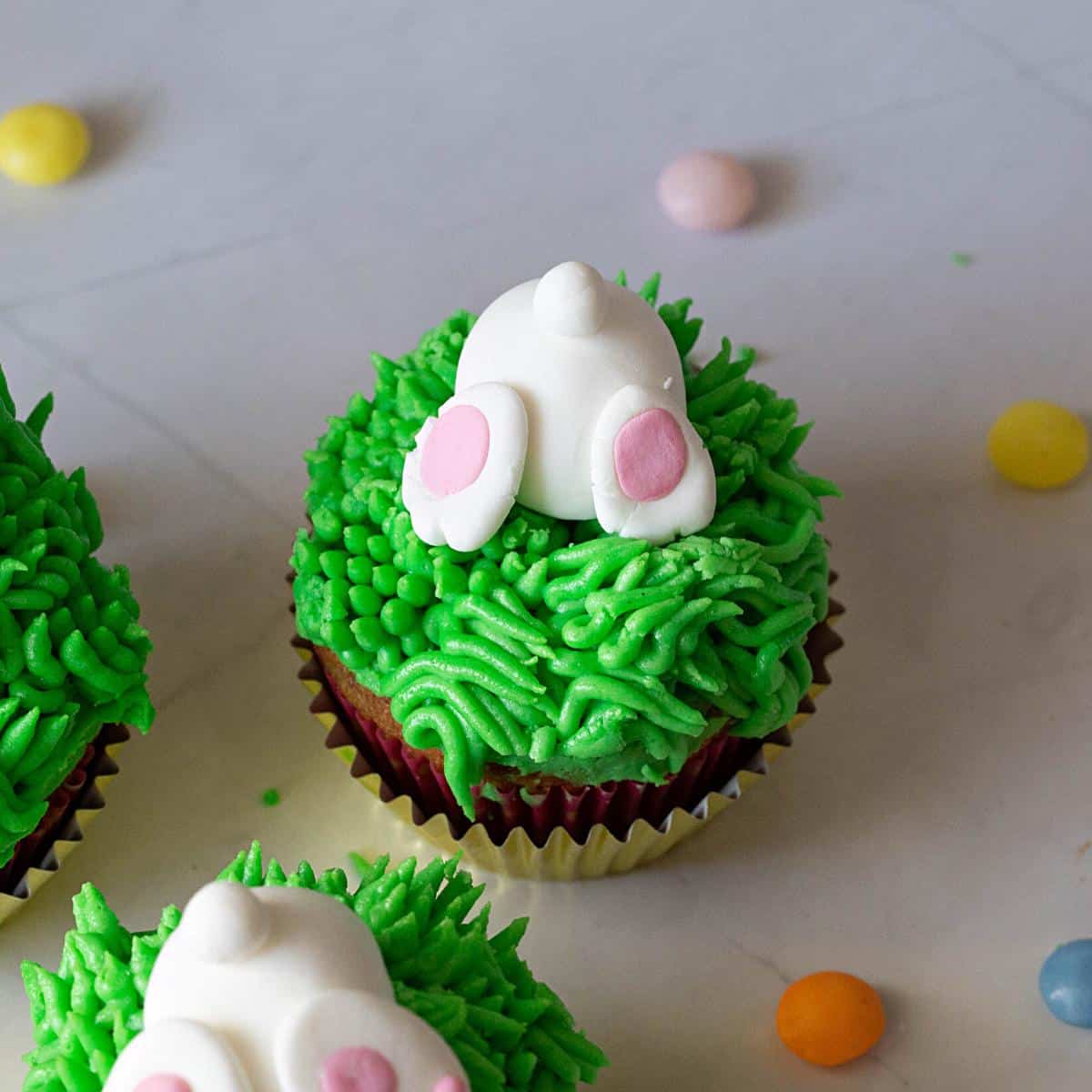 A cupcake with fondant bunny butt on grass.