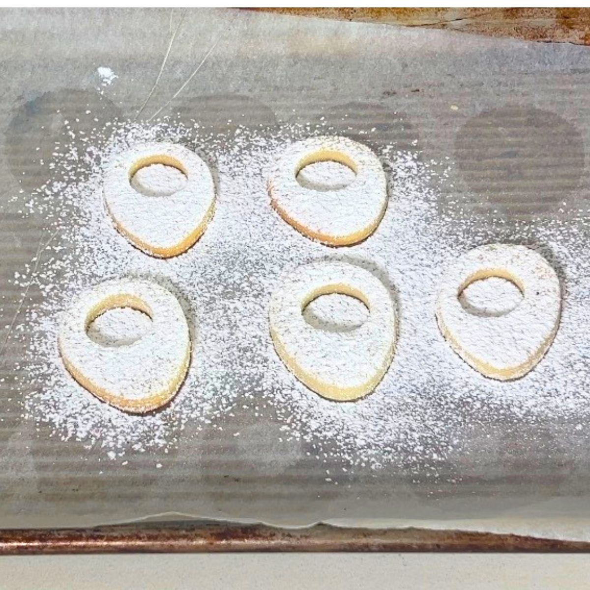 Top cookie of egg sandwich with powdered sugar.