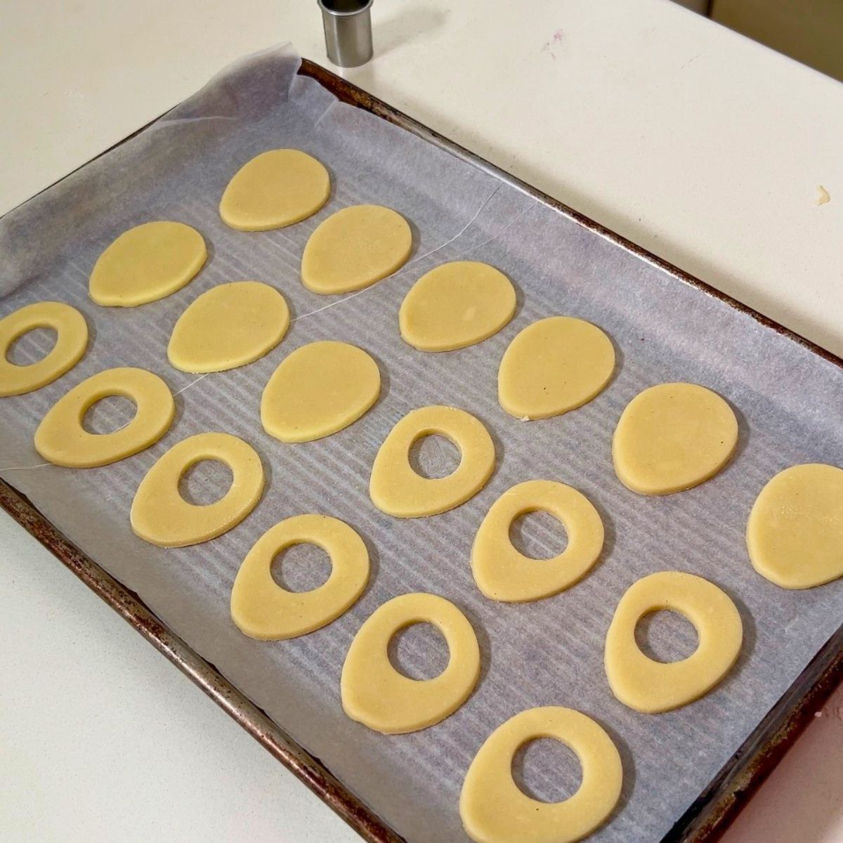 Baking tray with egg shaped cookie dough cut outs.