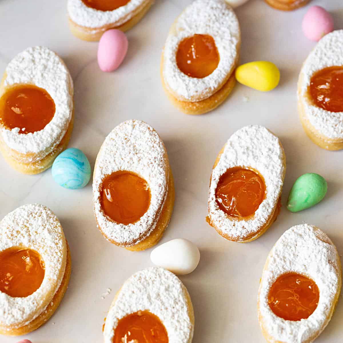 Oval cookies with apricot jam on a plate.