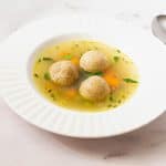 A shallow soup bowl with matzo balls.