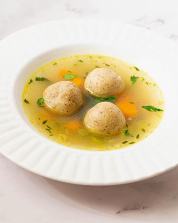 A shallow soup bowl with matzo balls.