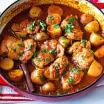 A dutch oven with braising chicken and gravy.