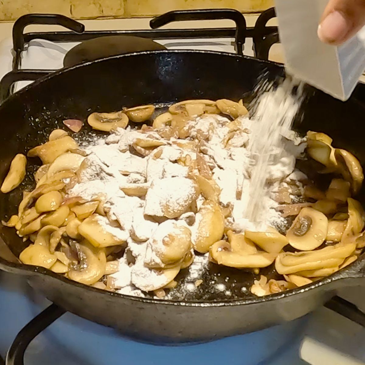 A cast iron skillet with mushroom and flour for thickening.