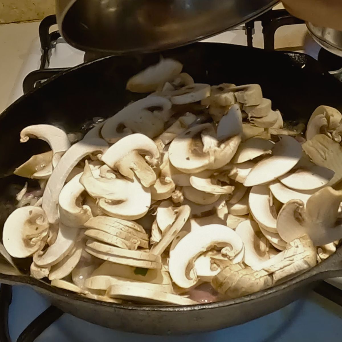 A cast iron skillet with sautéed mushrooms.