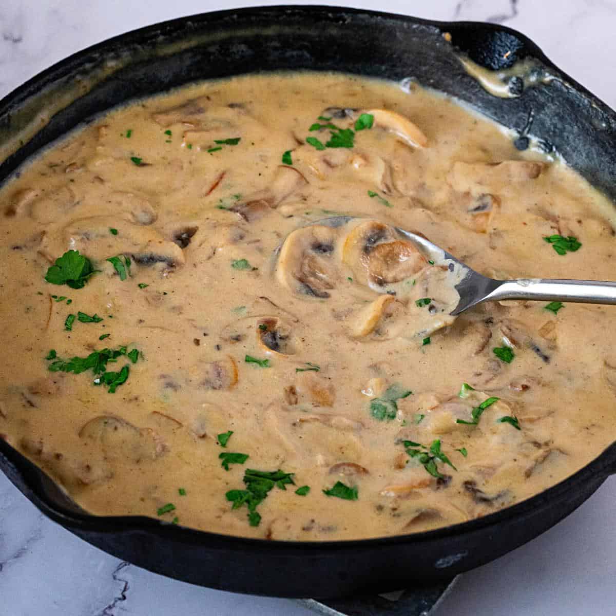 A skillet with mushrooms sauce.