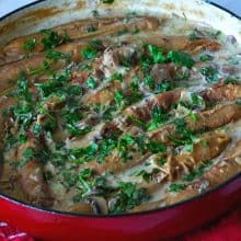 A dutch oven pot with sausages sautéed in mushroom gravy.