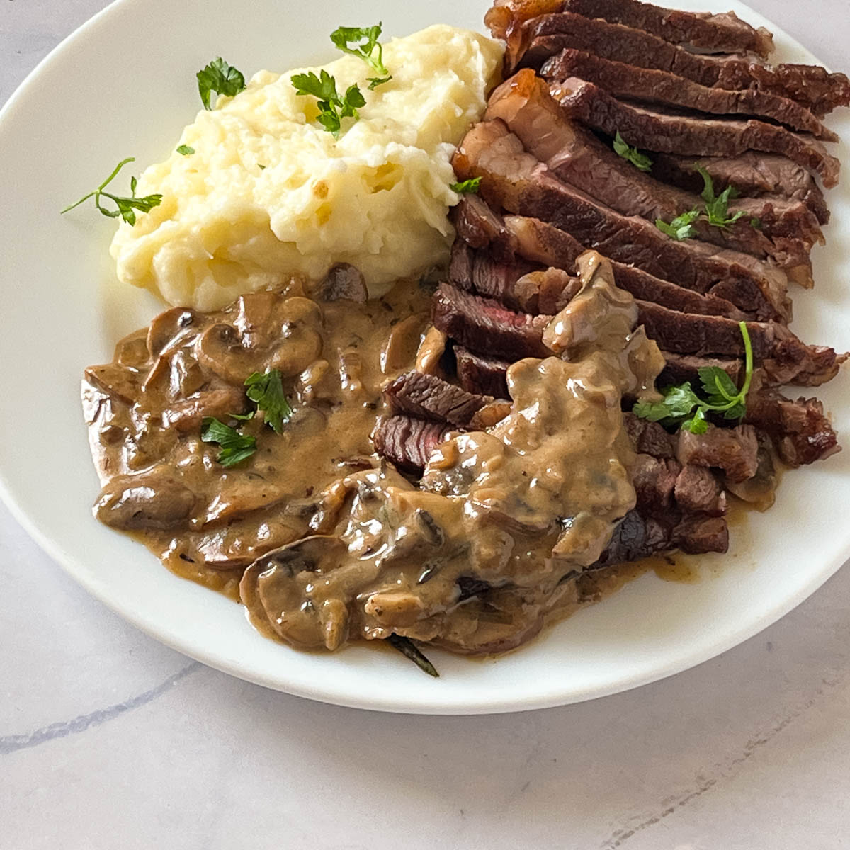 A plate with mushroom in red wine sauce over mashed potatoes.