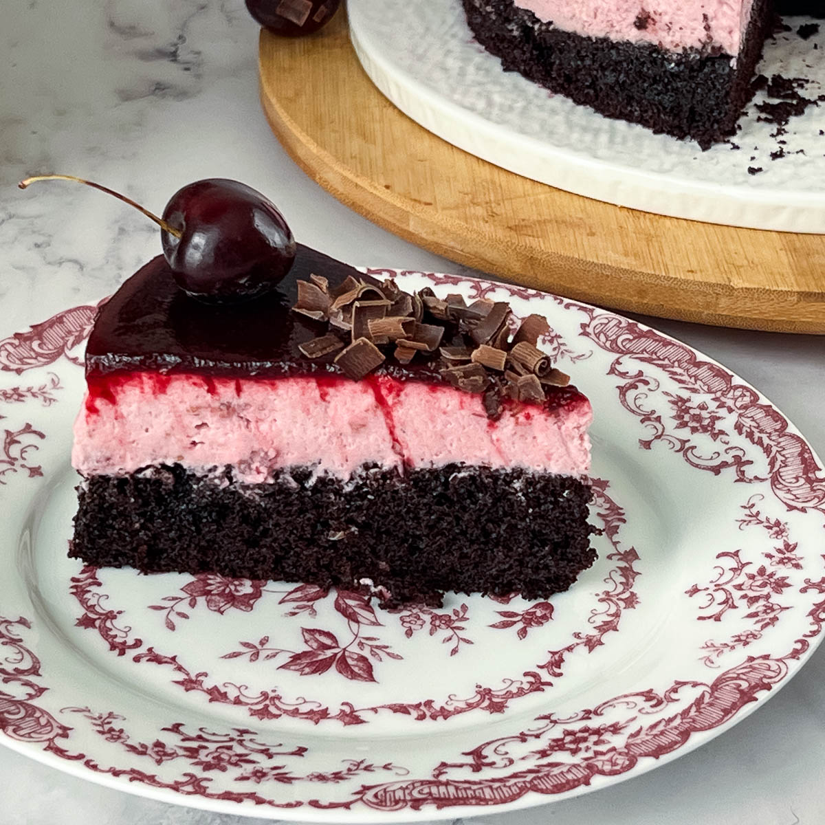 A slice of cherry mousse over chocolate cake.