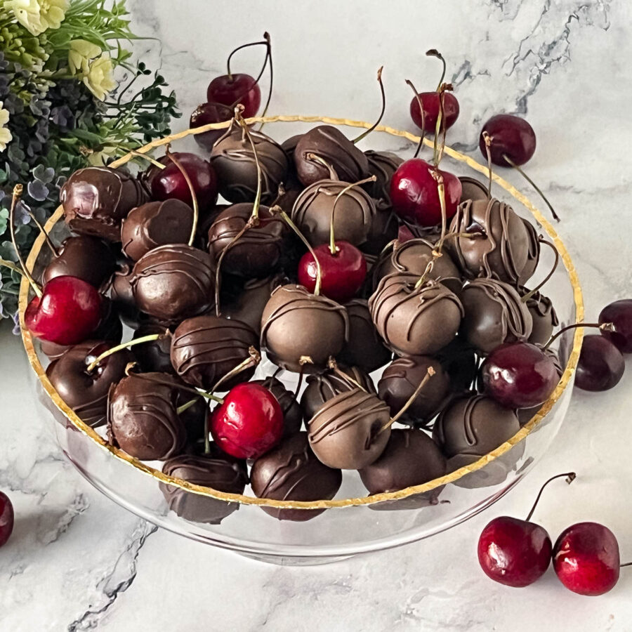 A platter with chocolate dipped cherries on the cake stand.
