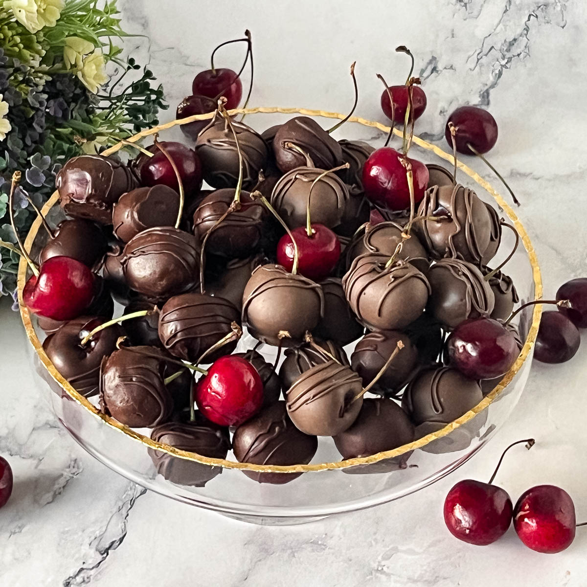 A platter with chocolate dipped cherries on the cake stand.