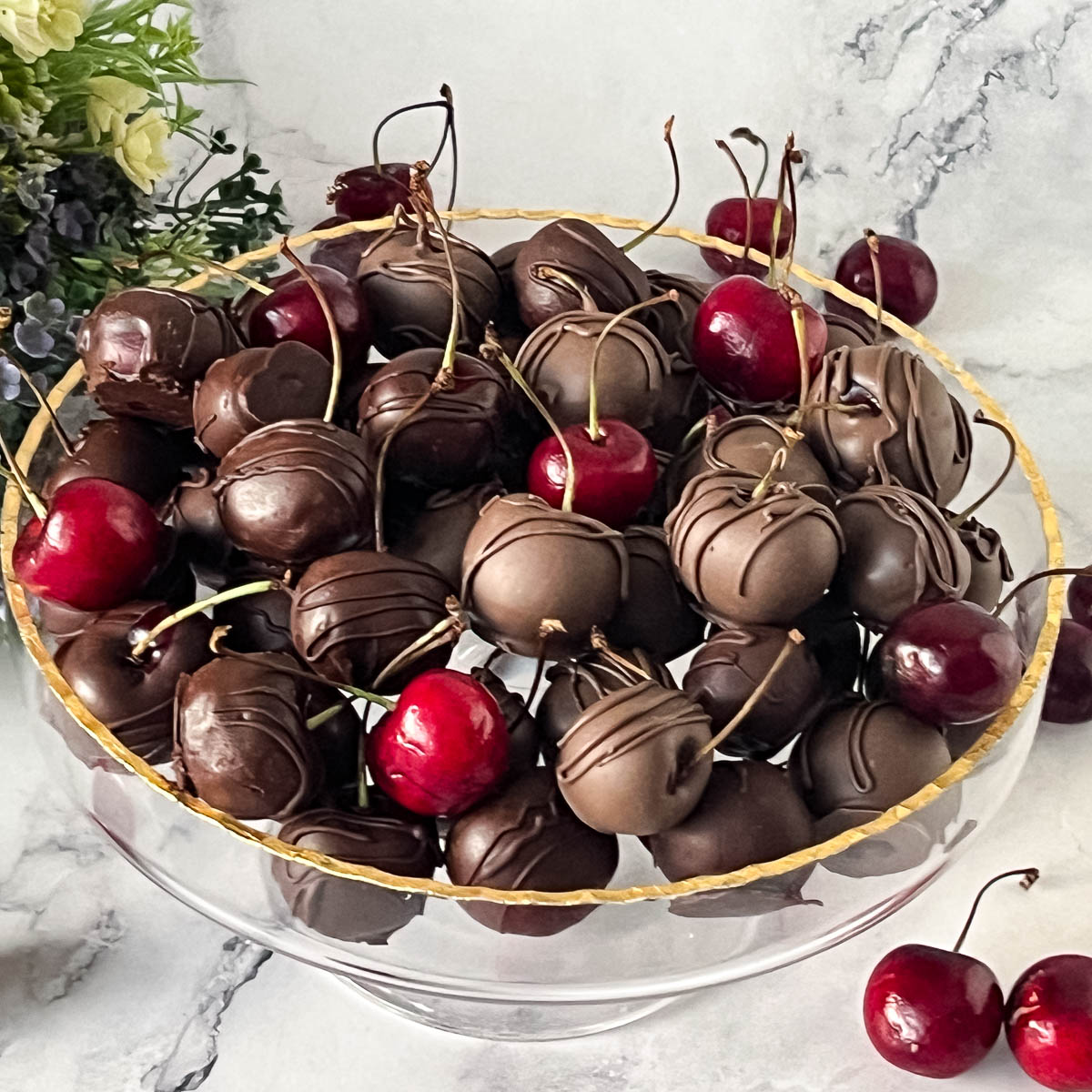 A cake stand with chocolate covered cherries.