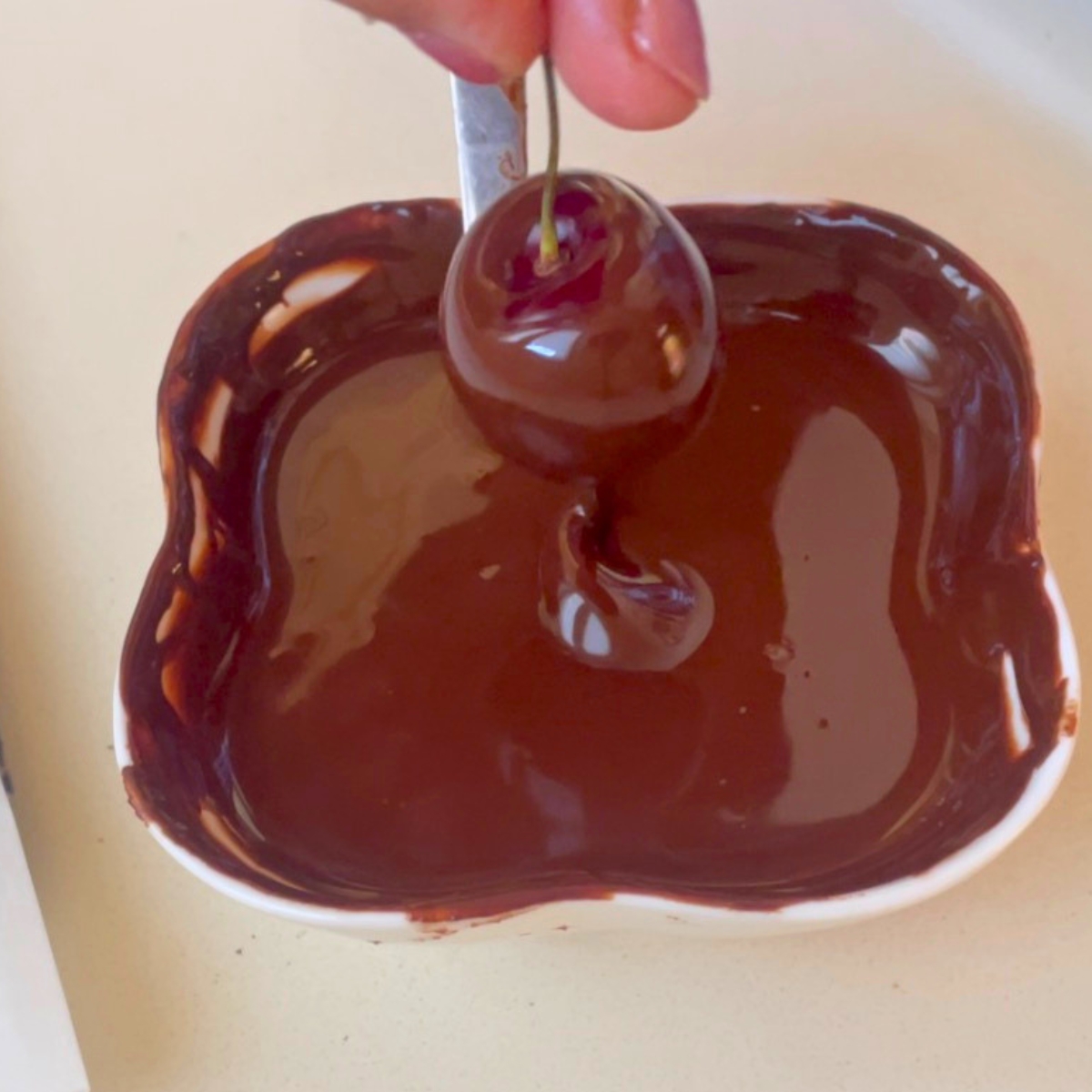 Dipping cherries in dark chocolate.