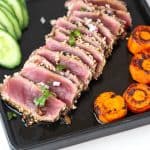 A black plate with seared tuna tataki.